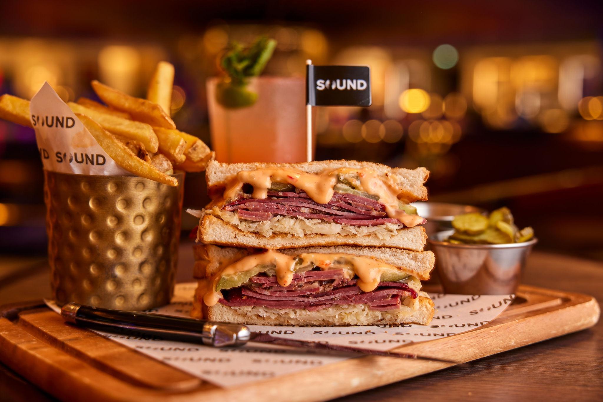 Sandwich with sauce oozing out, presented with fries
