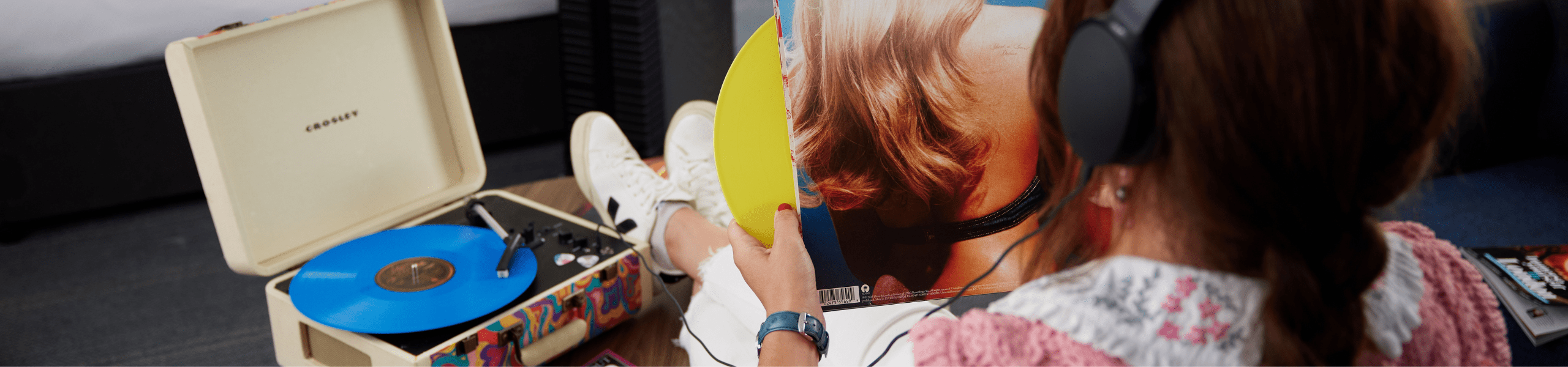 Person listening to vinyl on a Crosley turntable, holding a record sleeve