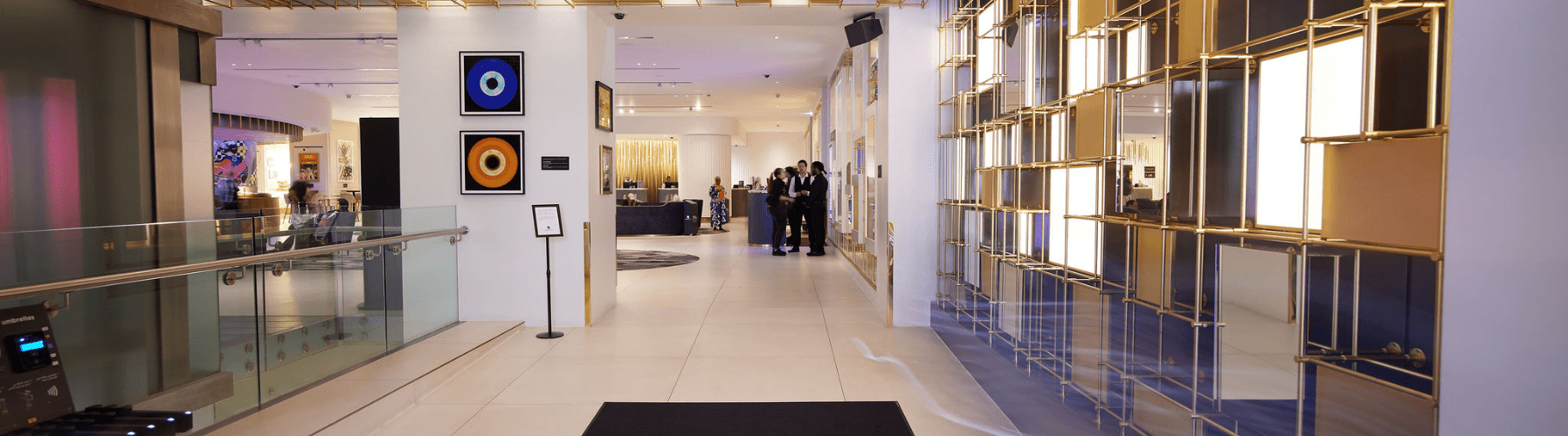 Modern hotel lobby with bright lighting, gold accents, and artwork on the walls