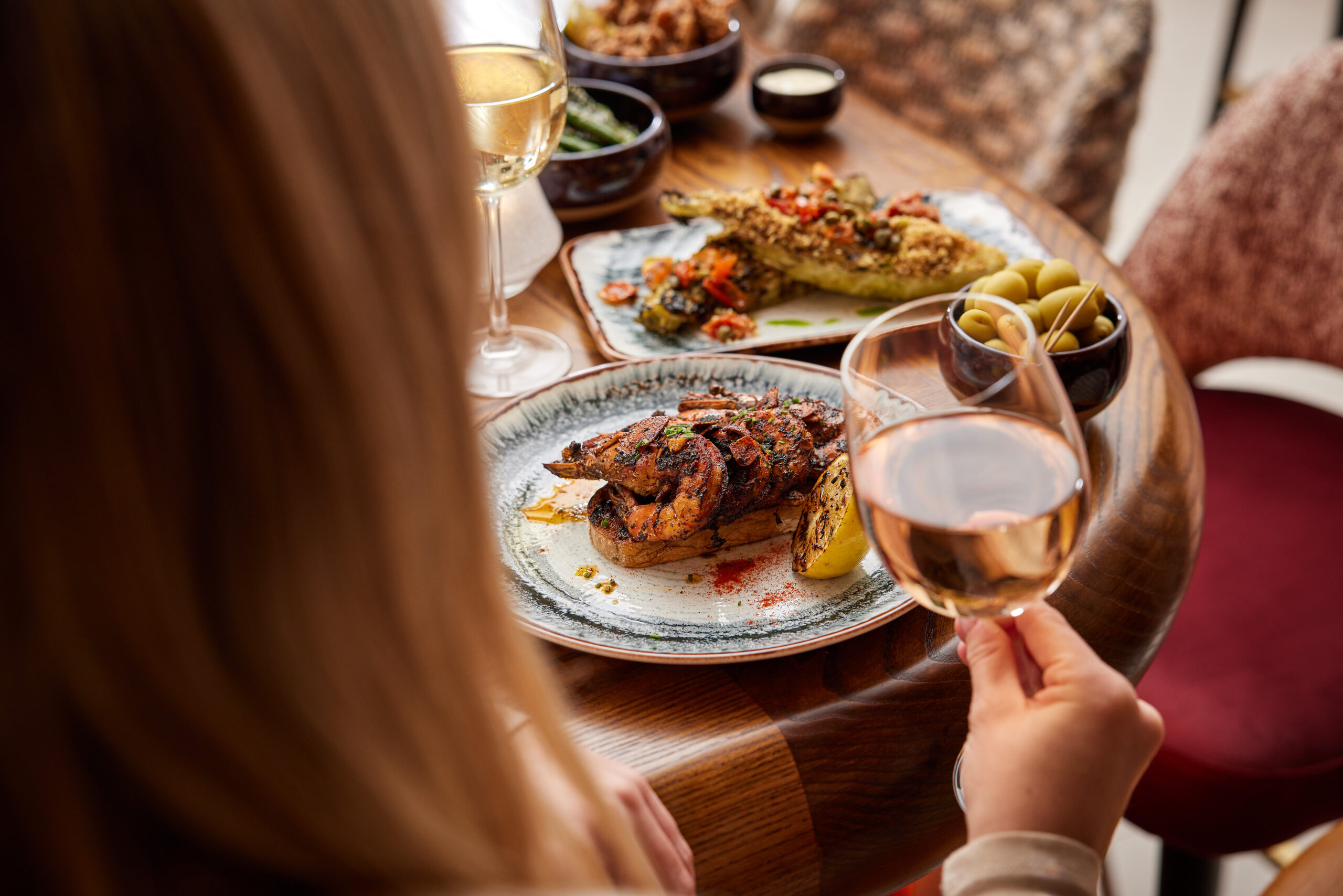 Plates of food at Lirica with glasses of wine