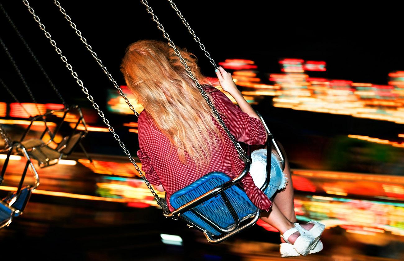 An atmospheric picture of girl on a fairground swing at night