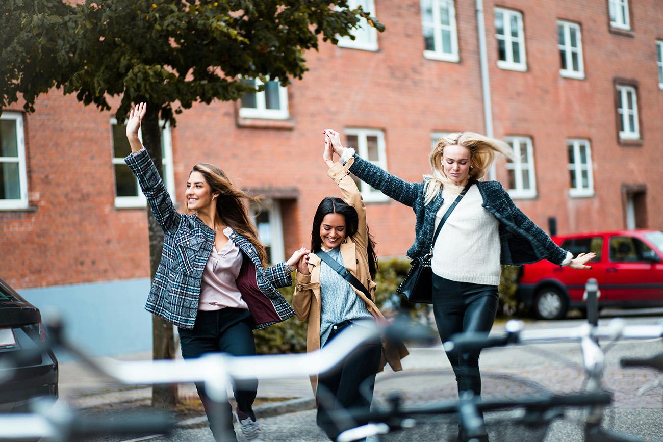 Group of women holding hands and jumping, looking stress free