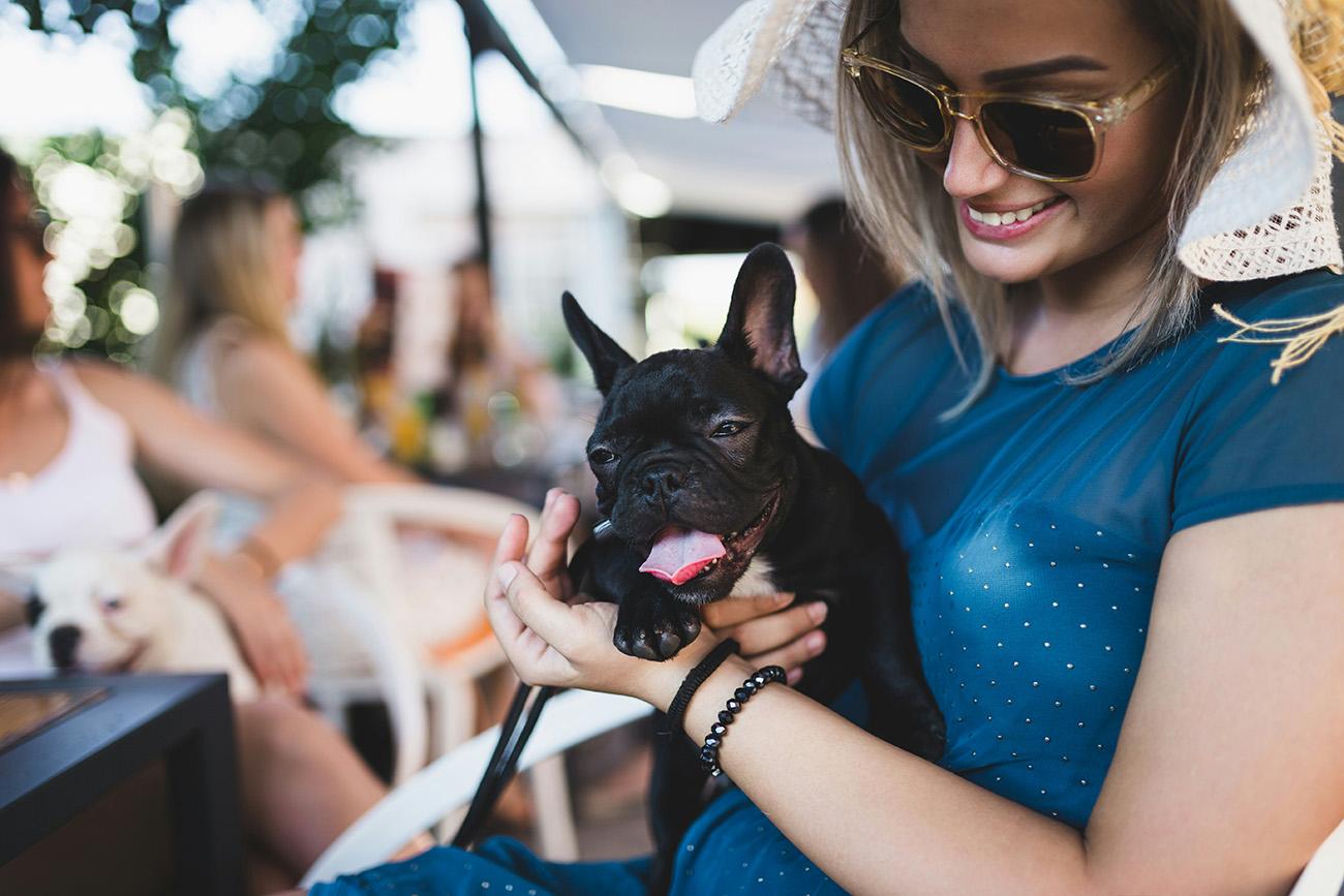 Woman in a cafe holding her dog looking happy