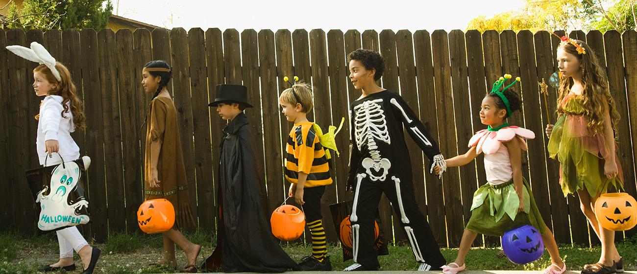A group of young children holding hands in halloween costumes