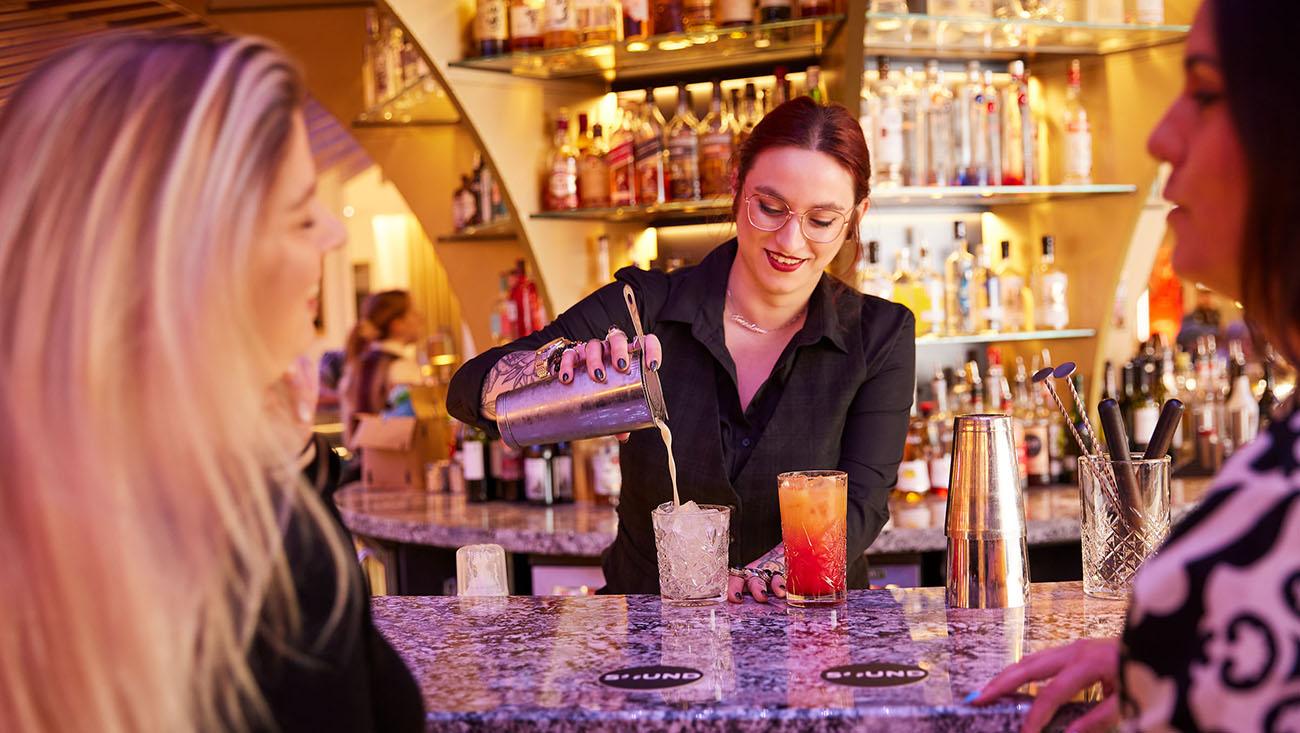 A female bar tender serving two delicious cocktails
