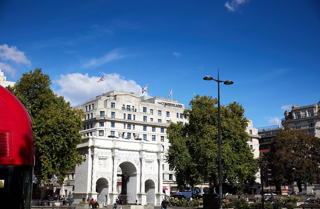 Marble Arch with The Cumberland hotel behind it beneath a bright blue sky.