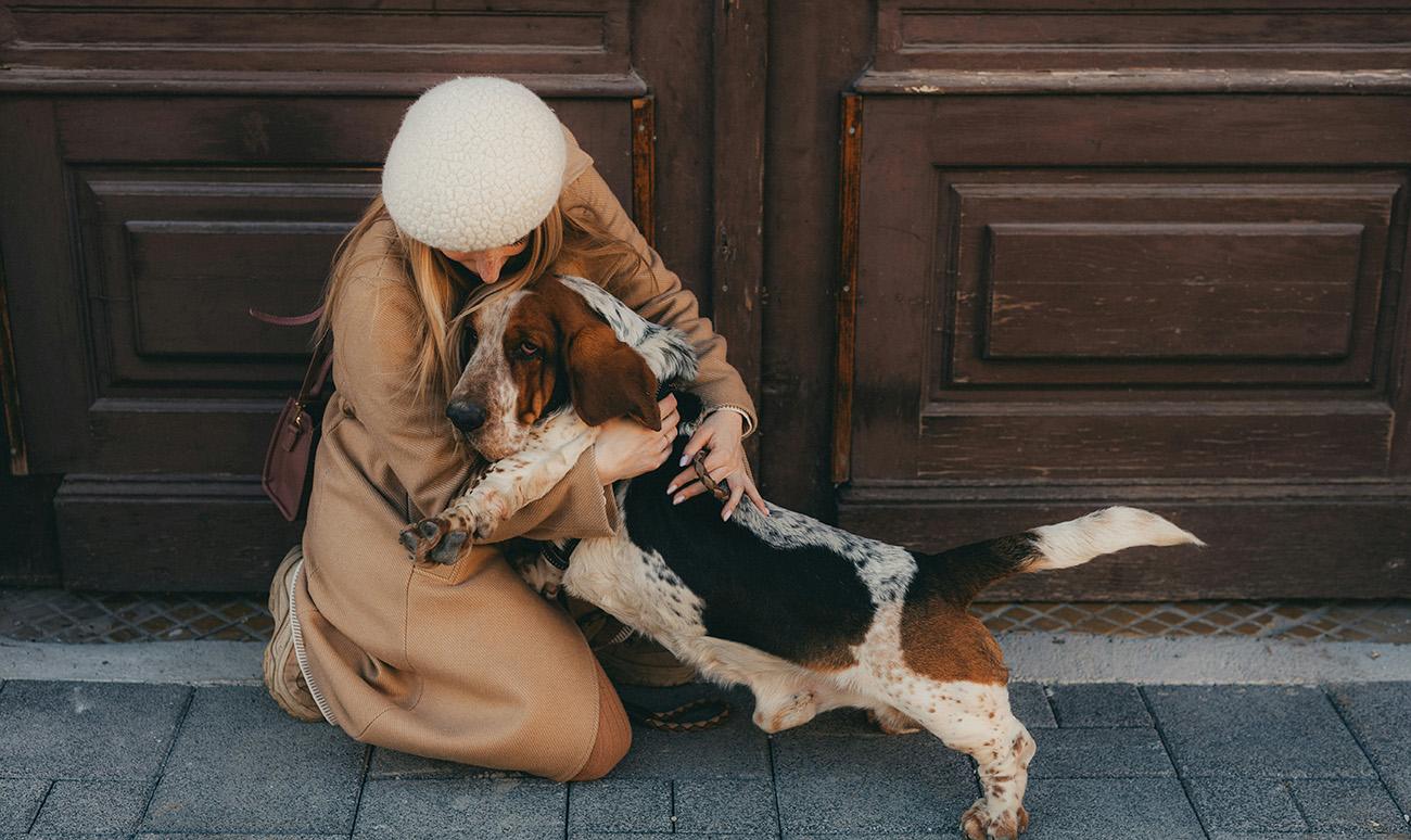 Woman in a beret cuddling her dog on the street