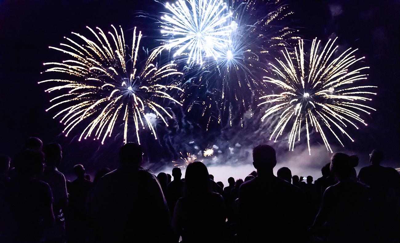 Fireworks in the night sky with silhouettes of a crowd